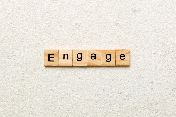 ENGAGE word written on wood block. ENGAGE text on cement table for your desing, concept.
