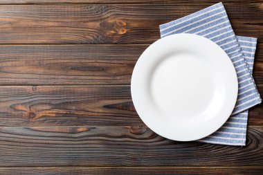 Renkli arka planda üst görünüm yiyecek için masa örtüsü üzerindeki boş yuvarlak beyaz tabak. Tasarımınız için boşluk olan peçeteye boş tabak.