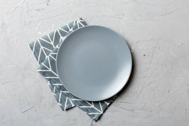 Renkli arka planda üst görünüm yiyecek için masa örtüsü üzerindeki boş yuvarlak gri tabak. Tasarımınız için boşluk olan peçeteye boş tabak.