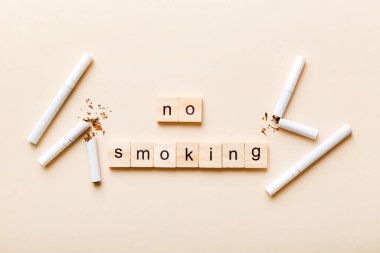 Sigara ve tahta bloklar, masa arkasında kırık sigara kum saati ile tütün günü yok, saat sağlığı konsepti. Sigarayı bırakma zamanı..