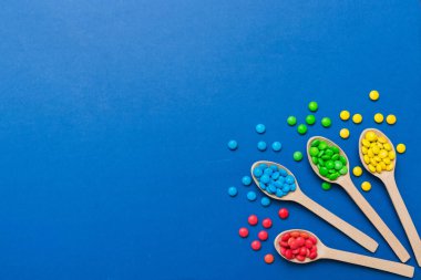 Renkli arka planda kaşık üzerinde renkli tatlı şekerler. Fotokopi alanı ile şekerleme dekoru üst görünümü.