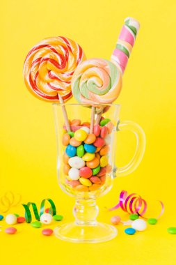 Masanın üzerinde açık arkaplanda renkli şekerler. Büyük kıvrımlı lolipoplar. Şekerci dükkanından leziz şekerlerle dolu yaratıcı bir kavanoz konsepti.