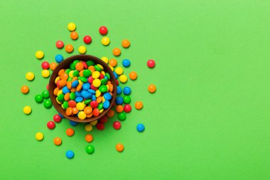 Renkli arka planda bir kasede çok renkli şekerler. Doğum günü ve tatil konsepti. Kopyalama alanı olan üst görünüm.