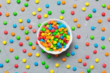 Renkli arka planda bir kasede çok renkli şekerler. Doğum günü ve tatil konsepti. Kopyalama alanı olan üst görünüm.