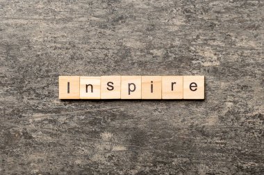 Tahta blokta yazılmış ilham verici bir kelime. Deksing, konsept için çimento masadaki metne ilham ver.