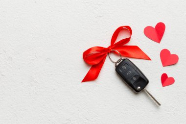 Siyah araba anahtarı, renkli arka planda kırmızı kalp ve kurdele olan hediye kutusunda. Sevgililer Günü Kompozisyonu Üst Görünüm.
