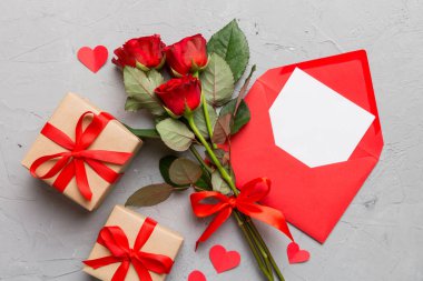 Zarflı sevgililer günü kompozisyonu, gül çiçeği ve kırmızı kalp masada. Üst manzara, düz yatış. Tatil kavramı.