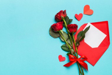 Zarflı sevgililer günü kompozisyonu, gül çiçeği ve kırmızı kalp masada. Üst manzara, düz yatış. Tatil kavramı.