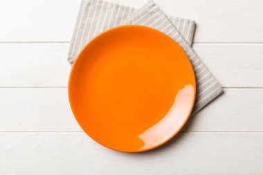 Renkli arka planda üst görünüm yiyecek için masa örtüsü üzerindeki boş yuvarlak kırmızı tabak. Tasarımınız için boşluk olan peçeteye boş tabak.