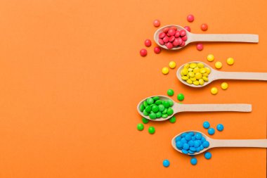 Renkli arka planda kaşık üzerinde renkli tatlı şekerler. Fotokopi alanı ile şekerleme dekoru üst görünümü.
