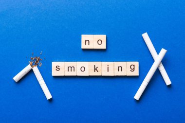 Sigara ve tahta bloklar, masa arkasında kırık sigara kum saati ile tütün günü yok, saat sağlığı konsepti. Sigarayı bırakma zamanı..