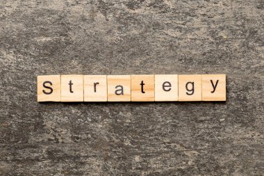 Tahta blokta STRATEGY kelimesi yazıyor. Beton masadaki STRATEGY metin desing, konsept için.