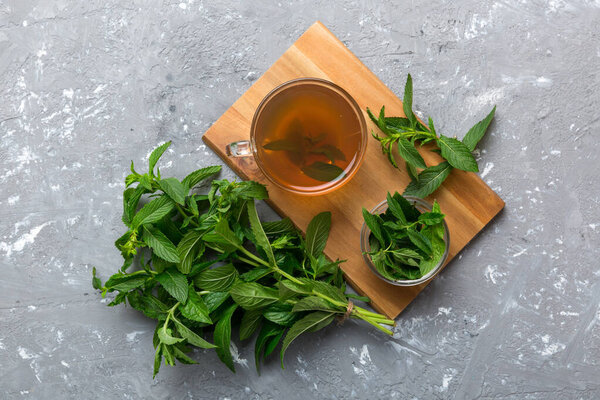 Чашка мятного чая на фоне стола. Зеленый чай со свежим мятным видом сверху с копировальным пространством.