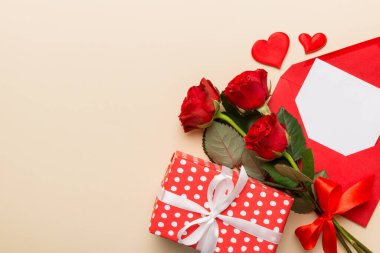 Zarflı sevgililer günü kompozisyonu, gül çiçeği ve kırmızı kalp masada. Üst manzara, düz yatış. Tatil kavramı.