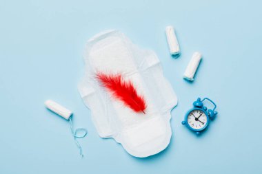 Alarm saatini hijyenik kadın tamponları ve regl pedleri ile çalıyor. Tıbbi konsept kadın kritik günler ve regl dönemi. Kadın günlük hijyen. Boşluğu kopyala.