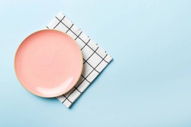 Renkli arka planda üst manzara. Yemek için masa örtüsü üzerine yuvarlak pembe tabak. Tasarımınız için boşluk olan peçeteye boş tabak.