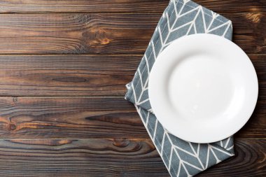 Renkli arka planda üst görünüm yiyecek için masa örtüsü üzerindeki boş yuvarlak beyaz tabak. Tasarımınız için boşluk olan peçeteye boş tabak.