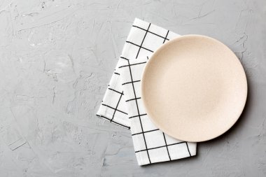 Renkli arka planda üst görünüm yiyecek için masa örtüsü üzerindeki boş yuvarlak beyaz tabak. Tasarımınız için boşluk olan peçeteye boş tabak.