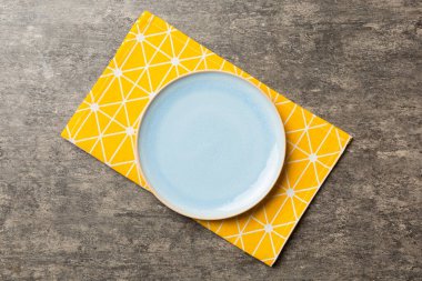 Renkli arkaplanda üst görünüm yiyecek için mavi tabak üzerinde boş. Tasarımınız için boşluk olan peçeteye boş tabak.