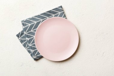 Renkli arka planda üst manzara. Yemek için masa örtüsü üzerine yuvarlak pembe tabak. Tasarımınız için boşluk olan peçeteye boş tabak.