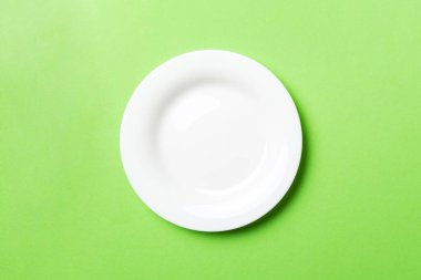 Renkli arka plan görüntüsünün üst görüntüsü yiyecek için boş yuvarlak beyaz tabak. Tasarımınız için alanı olan boş tabak.