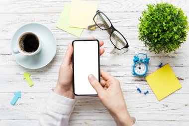 Mesajınız veya bilgi içeriğiniz için boş bir kopya ekranı olan akıllı telefonları tutan kadın ellerinin üst görünümü. üst görünümde telefon beyaz ekranı kullanan kadın eli.