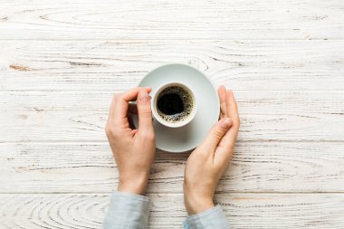 Renkli arka planda bir fincan kahve tutan minimalist stil bir kadın. Düz yerde, kapuçino bardağının üstünde. Metin için boş yer, kopyalama alanı. Kahve bağımlılığı. Üst manzara, düz uzanma.