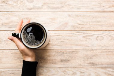 Renkli arka planda bir fincan kahve tutan minimalist stil bir kadın. Düz yerde, kapuçino bardağının üstünde. Metin için boş yer, kopyalama alanı. Kahve bağımlılığı. Üst manzara, düz uzanma.