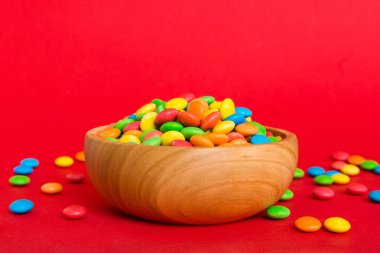 Renkli arka planda bir kasede çok renkli şekerler. Doğum günü ve tatil konsepti. Kopyalama alanı olan üst görünüm.