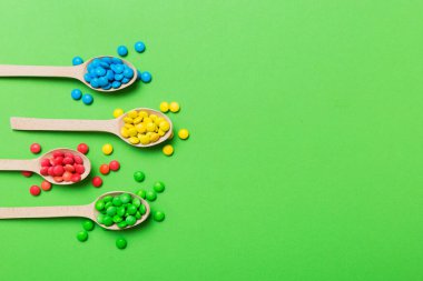 Renkli arka planda kaşık üzerinde renkli tatlı şekerler. Fotokopi alanı ile şekerleme dekoru üst görünümü.