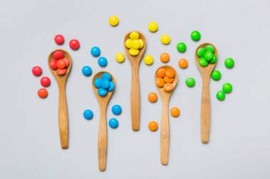 Renkli arka planda kaşık üzerinde renkli tatlı şekerler. Fotokopi alanı ile şekerleme dekoru üst görünümü.