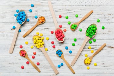 Renkli arka planda kaşık üzerinde renkli tatlı şekerler. Fotokopi alanı ile şekerleme dekoru üst görünümü.