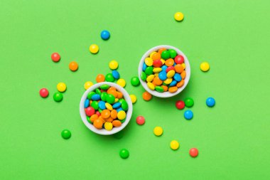 Renkli arka planda bir kasede çok renkli şekerler. Doğum günü ve tatil konsepti. Kopyalama alanı olan üst görünüm.