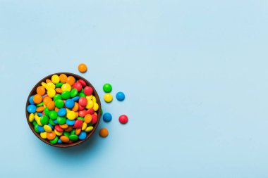 Renkli arka planda bir kasede çok renkli şekerler. Doğum günü ve tatil konsepti. Kopyalama alanı olan üst görünüm.