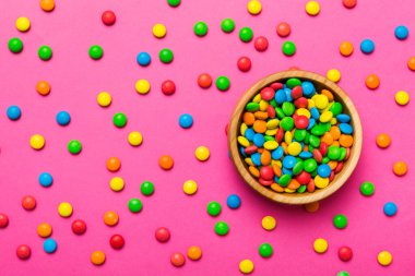 Renkli arka planda bir kasede çok renkli şekerler. Doğum günü ve tatil konsepti. Kopyalama alanı olan üst görünüm.