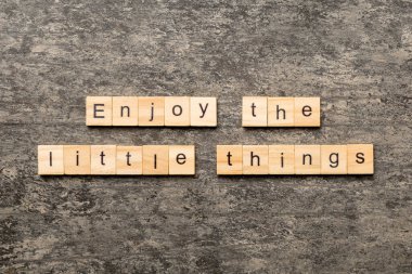 Tahta blokta yazan küçük sözcüğün tadını çıkar. Çimento masasındaki küçük şeylerin tadını çıkar..