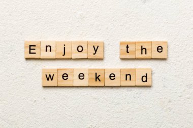 Enjoy the weekend word written on wood block. Enjoy the weekend text on cement table for your desing, Top view concept. clipart