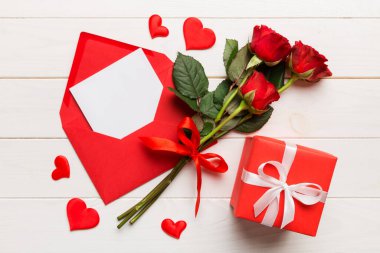 Zarflı sevgililer günü kompozisyonu, gül çiçeği ve kırmızı kalp masada. Üst manzara, düz yatış. Tatil kavramı.