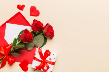 Zarflı sevgililer günü kompozisyonu, gül çiçeği ve kırmızı kalp masada. Üst manzara, düz yatış. Tatil kavramı.