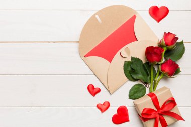 Zarflı sevgililer günü kompozisyonu, gül çiçeği ve kırmızı kalp masada. Üst görünüm, düz görünüm, kopyalama alanı Tatil kavramı.