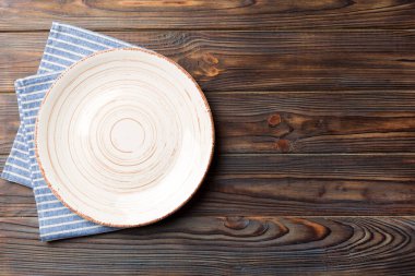 Renkli arka planda üst görünüm yiyecek için masa örtüsü üzerindeki boş yuvarlak beyaz tabak. Tasarımınız için boşluk olan peçeteye boş tabak.