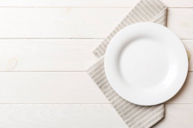 Renkli arka planda üst görünüm yiyecek için masa örtüsü üzerindeki boş yuvarlak beyaz tabak. Tasarımınız için boşluk olan peçeteye boş tabak.
