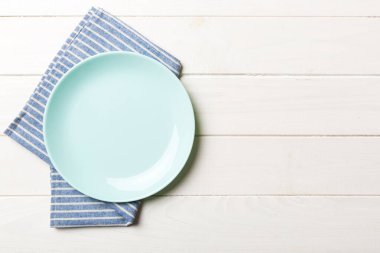 Renkli arkaplanda üst görünüm yiyecek için mavi tabak üzerinde boş. Tasarımınız için boşluk olan peçeteye boş tabak.