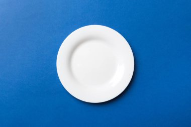 Renkli arka plan görüntüsünün üst görüntüsü yiyecek için boş yuvarlak beyaz tabak. Tasarımınız için alanı olan boş tabak.