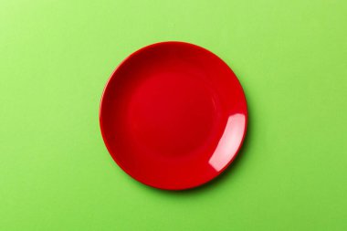 Renkli arka planın üst görüntüsü yiyecek için boş yuvarlak kırmızı tabak. Tasarımınız için alanı olan boş tabak.