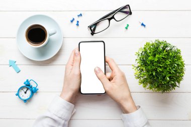 Mesajınız veya bilgi içeriğiniz için boş bir kopya ekranı olan akıllı telefonları tutan kadın ellerinin üst görünümü. üst görünümde telefon beyaz ekranı kullanan kadın eli.
