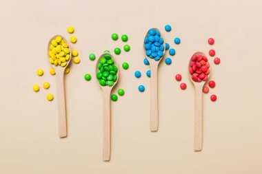 Renkli arka planda kaşık üzerinde renkli tatlı şekerler. Fotokopi alanı ile şekerleme dekoru üst görünümü.