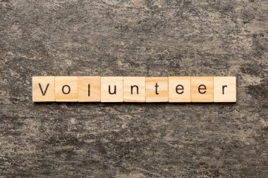 Tahta bloğa yazılmış gönüllü kelime. Gönüllü metin masa üzerinde, konsept.