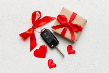 Siyah araba anahtarı, renkli arka planda kırmızı kalp ve kurdele olan hediye kutusunda. Sevgililer Günü Kompozisyonu Üst Görünüm.