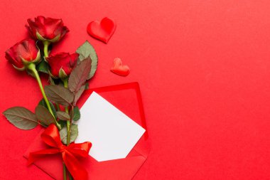 Zarflı sevgililer günü kompozisyonu, gül çiçeği ve kırmızı kalp masada. Üst manzara, düz yatış. Tatil kavramı.